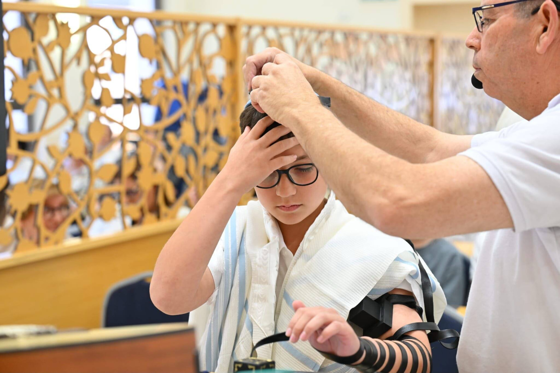 עמיחי מסייע לנער להניח את תפילין של ראש
